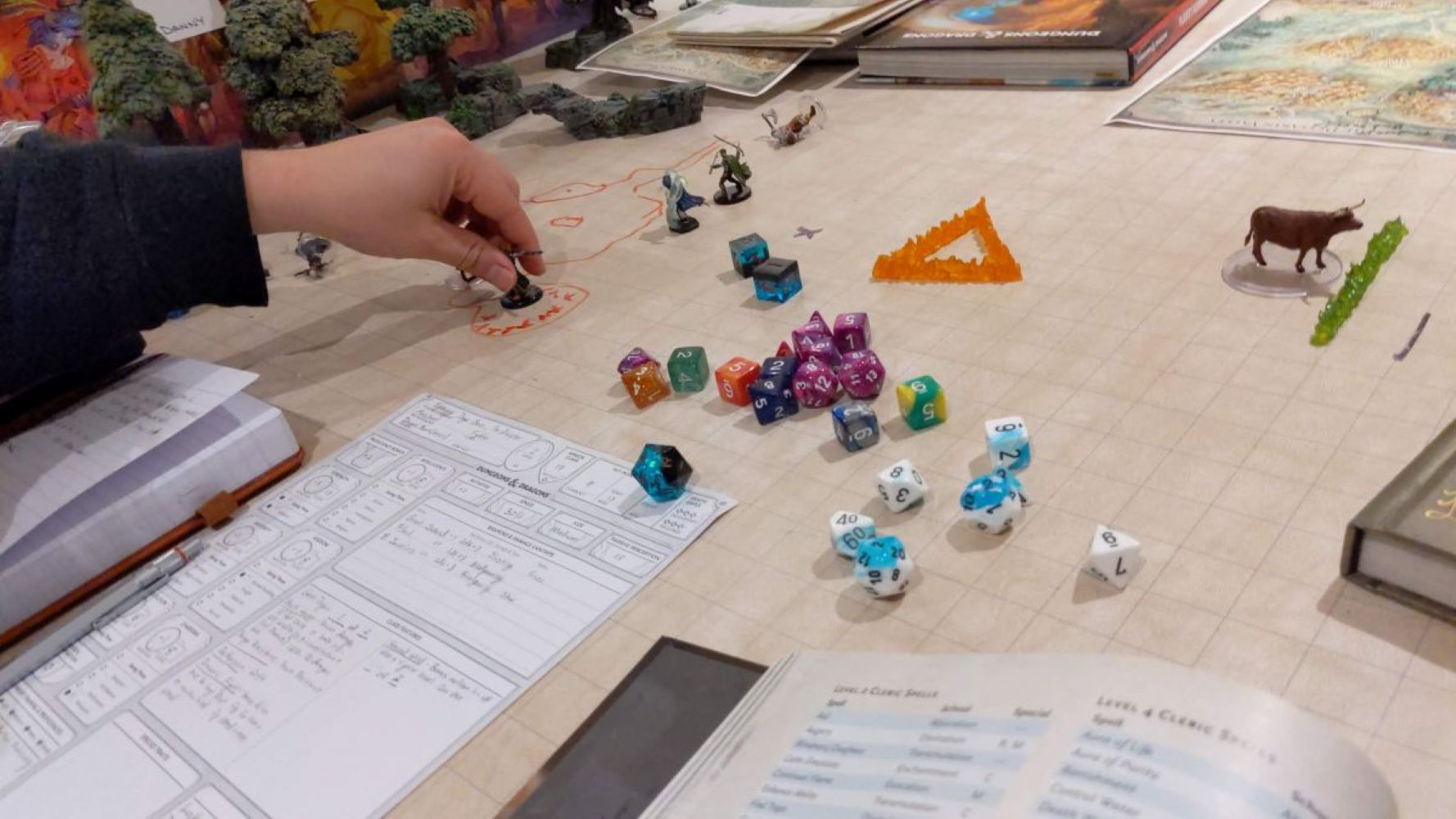 A real tabletop setup prepared with modular dungeon tiles, hero miniatures, dice and character sheets